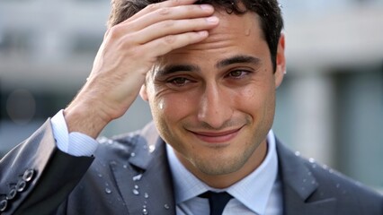 Mental Health for Entrepreneurs Man in a suit wipes sweat from his forehead, showing signs of heat or stress, with a slight smile.
