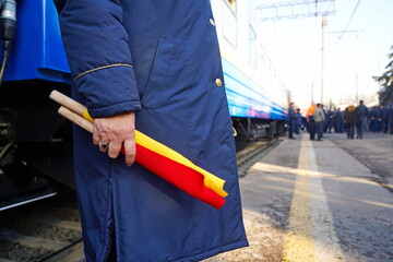 A signal flag in the hands of a passenger train conductor.