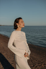 A young pregnant woman is walking on the beach in the evening. The concept of motherhood and childbirth