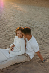 Happy young couple on the beach. Pregnant woman and man on a walk. Family expecting a child.