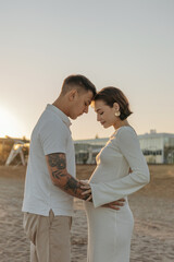 Happy young couple on the beach. Pregnant woman and man on a walk. Family expecting a child.