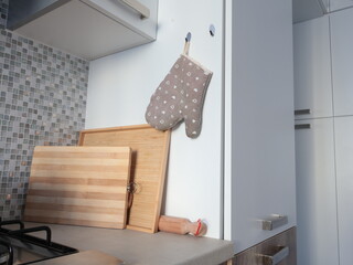 Pot holders with heart pattern in kitchen. Interior and cutting boards near kitchen cabinets. Interior design. 