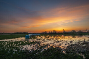 Colorful clouds and sky after sunset over a wet meadow
