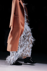 Fashion classy details of brown jacket, fluffy dress and leather boots, fancy cloth on black background