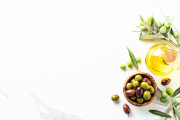 Olives in wooden bowl and fresh olive tree branch at black background.
