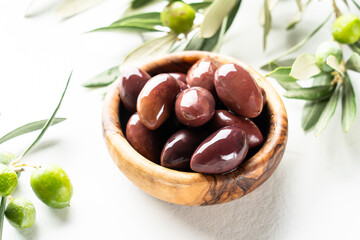 Olives in the bowl at white table.