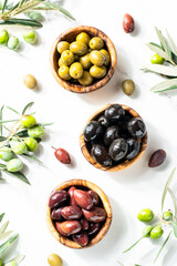 Olives in wooden bowls and Olive oil in the bottle at white table.
