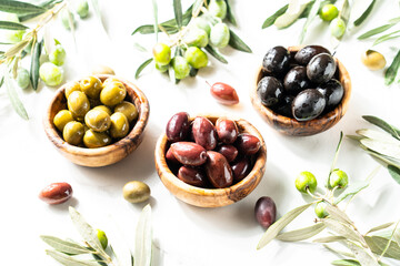 Olives and Olive oil in the bottle at white table.