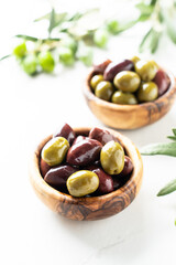 Olives and Olive oil in the bottle at white table.