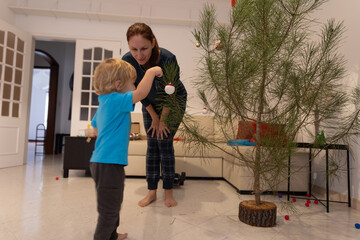 Mother and child decorating christmas tree for winter holiday