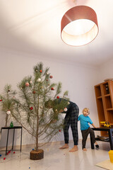 Father and son decorating natural pine christmas tree