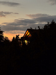 Cottage Roof Silhouette in Forest Under Orange Sunset Sky