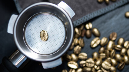 Single golden coffee bean placed in an espresso portafilter, surrounded by gold-colored...