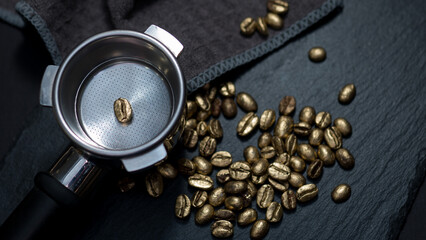 Single golden coffee bean placed in an espresso portafilter, surrounded by gold-colored...