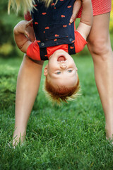 Happy laughing baby boy. Mom and son are cheerfully playing together in the park in the summer. Mother is holding kid. Protection kids from insects