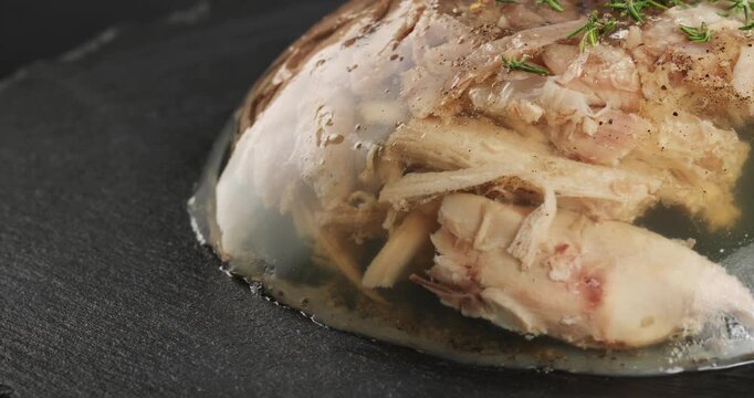 Aspic jellied meat on a dark background. Close-up footage on the rotating table.