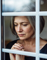 Frau mit nachdenklichen &auml;ngstlichen Blick aus dem Fenster