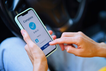 Hand using smartphone to complete mobile payment in car