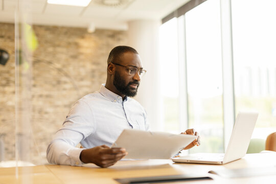 Businessman working with paperwork and laptop in modern office