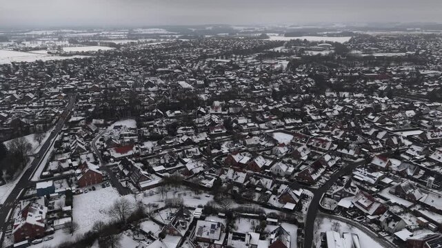 Cold frosty and snowy winter in american town with leafless trees and snow-covered houses. Aerial flyover wide shot. High angle. Foggy and cloudy sky in neighborhood of United States. Peaceful scene.