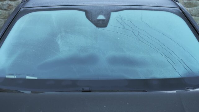 4K: Scraping Snow and Ice off a Car Window Windscreen Windshield in the cold Winter. Stock Video Clip Footage