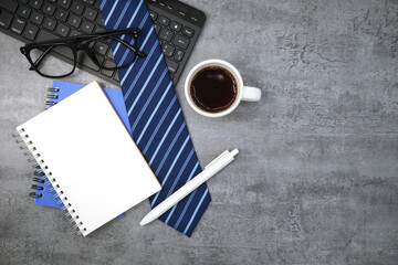 Necktie with notebook and keyboard on stone texture background. Business desk office. Top view