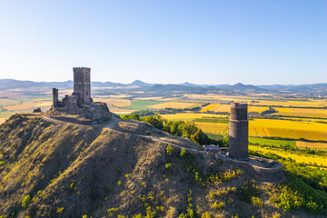 Hazmburk Castle ruins rise majestically in Czechia, surrounded by lush fields and rolling hills. This medieval structure stands as a testament to history amid the stunning Central Bohemian Uplands.