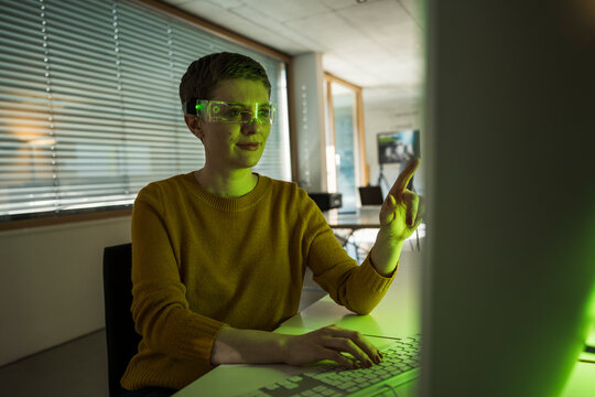 Woman in modern office using computer and VR glasses