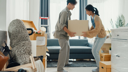 Young Asian couple help each other moving carton box full of stuff get some rest sit on sofa couch in living room at new house. Husband and wife move new house, Apartment Rent And Ownership Concept.