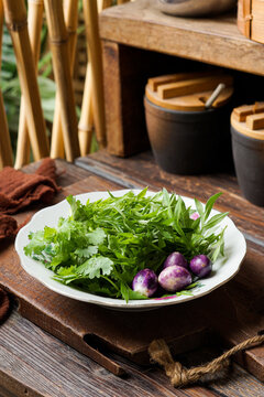 This traditional Malay ulam features fresh purple mini eggplant ulam raja and coriander leaves served raw highlighting natural flavors crisp texture and healthy local herbs commonly enjoyed with rice 