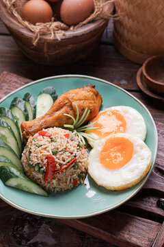 Nasi Goreng served with fried egg fried chicken and fresh cucumber ulam is a classic Southeast Asian meal combining savory flavors, crispy textures, and traditional home cooked comfort food.