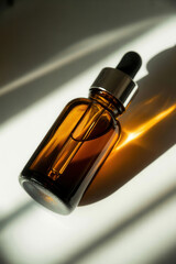 Brown glass dropper bottle with black lid and liquid inside casting shadow on white surface
