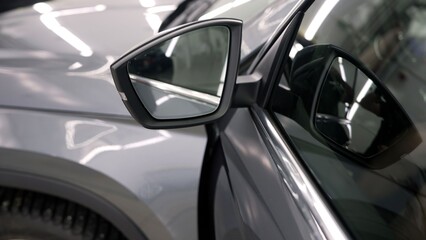 Flawless grey car body reflecting bright hexagonal lights after a professional detailing and ceramic coating application in a clean garage