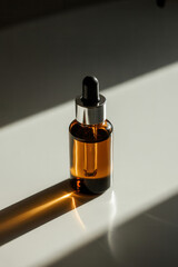 Glass dropper bottle with amber liquid casting shadow on white surface in bright light