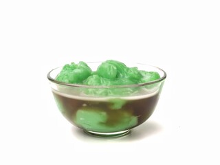 Indonesian green rice pudding with palm sugar syrup (Bubur sumsum pandan) served in a glass bowl isolated on white background. popular Indonesian street food and takjil for Iftar