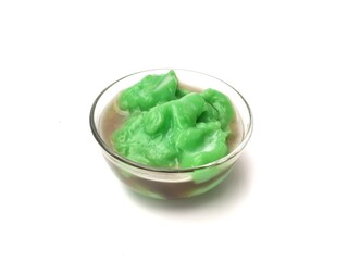 Indonesian green rice pudding with palm sugar syrup (Bubur sumsum pandan) served in a glass bowl isolated on white background. popular Indonesian street food and takjil for Iftar. High angle view 