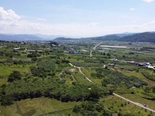 長野の中野市の農園と夏の青空　雄大な山並みと果樹園の風景（ドローン空撮）