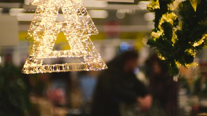 Festive Christmas decorations illuminate a busy shopping mall interior. Shoppers browse for gifts under sparkling holiday lights, capturing the spirit of the season.