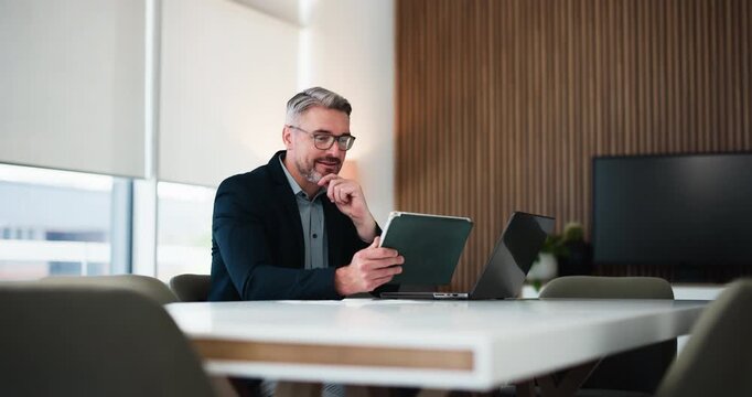 Businessman, reading and tablet in office with laptop for research, financial proposal and audit. Mature person, review or evaluation in workplace with computer, tech and planning for finance report.