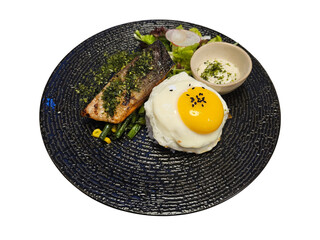 A gourmet meal featuring grilled salmon with herbs, a sunny-side-up fried egg over rice, green beans, and a fresh side salad on a dark textured plate.