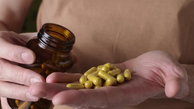 Bare-chested man frantically dumps supplement capsules into palm from amber bottle, overdose risk concept for health routine.