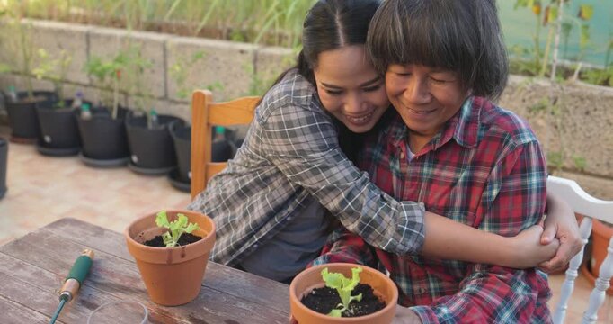 Asian mother and daughter having tender moment together while gardening at home terrace - Family lifestyle, love and nature concept