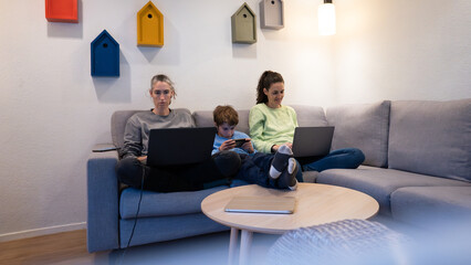 Family members using digital devices on couch at home