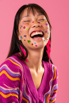 Beautiful asian woman portrait, asian woman laughing with face gems on pink background