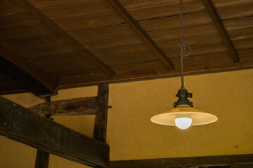 古民家の高い天井とレトロなペンダントライト　土壁と梁のある風景