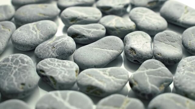 Collection of smooth gray pebbles with unique patterns, creating a natural and calming background.