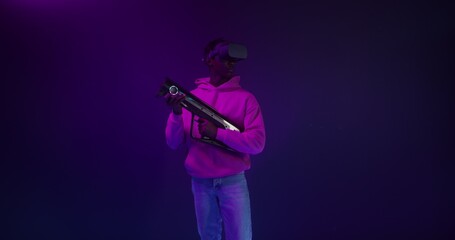 Fototapeta premium A man in a virtual reality headset with a blaster in his hands in a VR studio