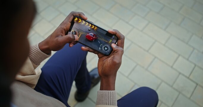 Man playing online racing game on mobile phone