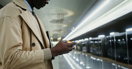 A man plays on a mobile phone while waiting train in the subway