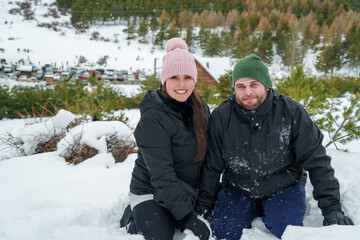 Happy couple enjoying winter vacation in snowy mountain landscape
